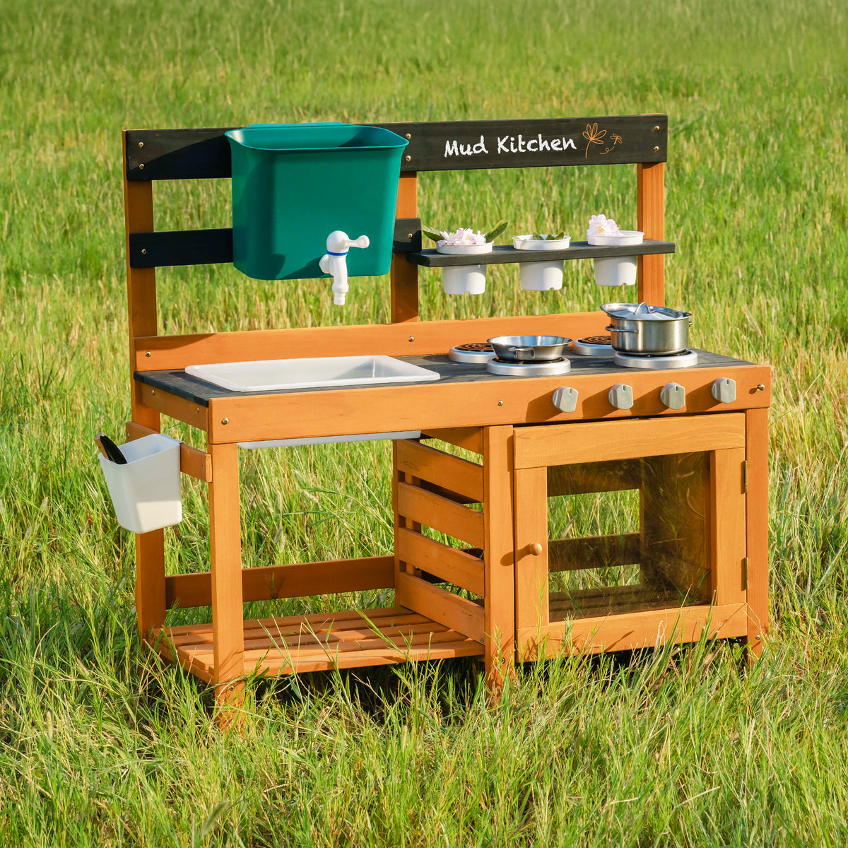 ROBUD Outdoor Mud Kitchen standalone front view showing full honey-toned wooden mud kitchen station with chalkboard, sink basin and stainless accessories in meadow