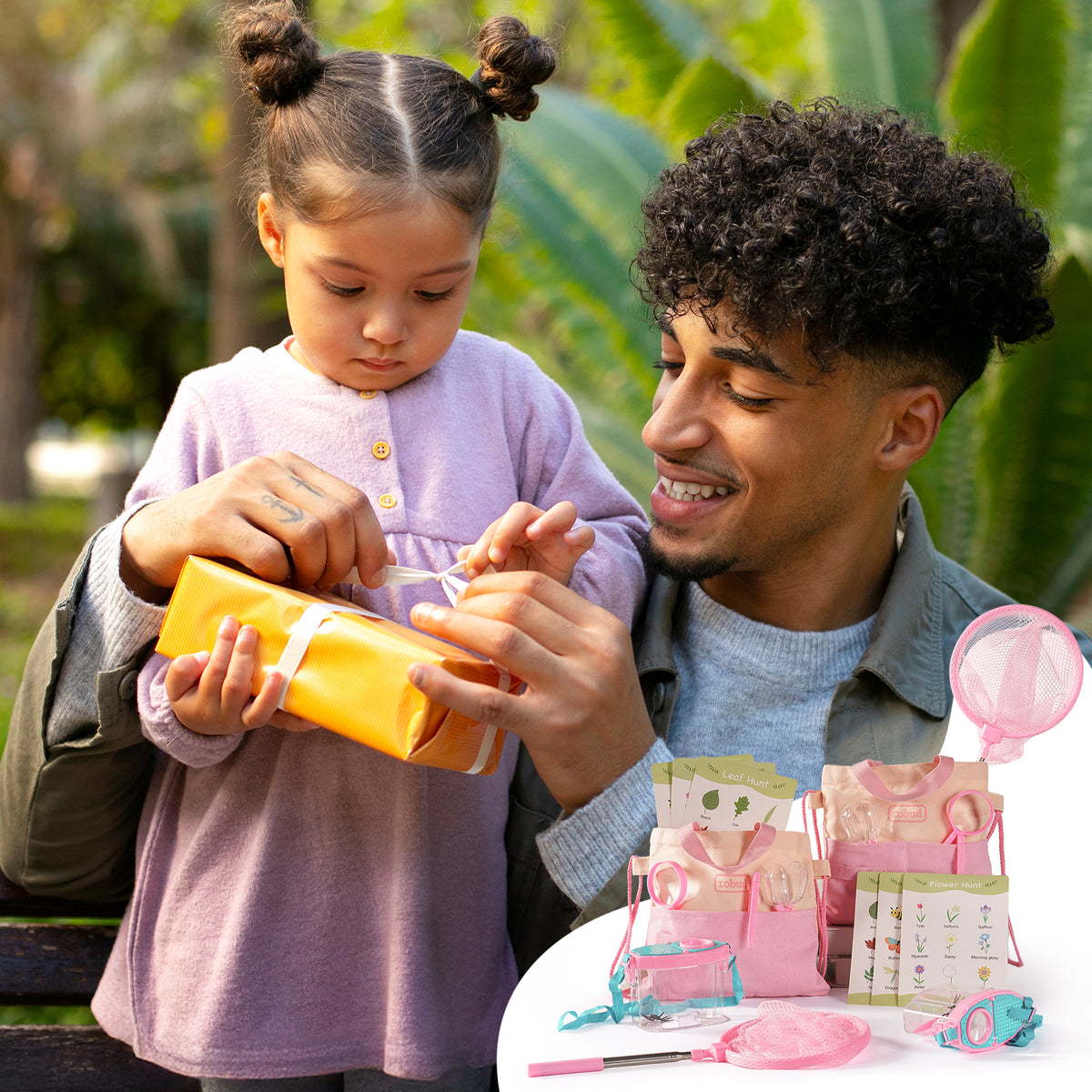 Two girls examining captured butterfly in ROBUD aqua bug container while pink binoculars and net hang nearby outdoors