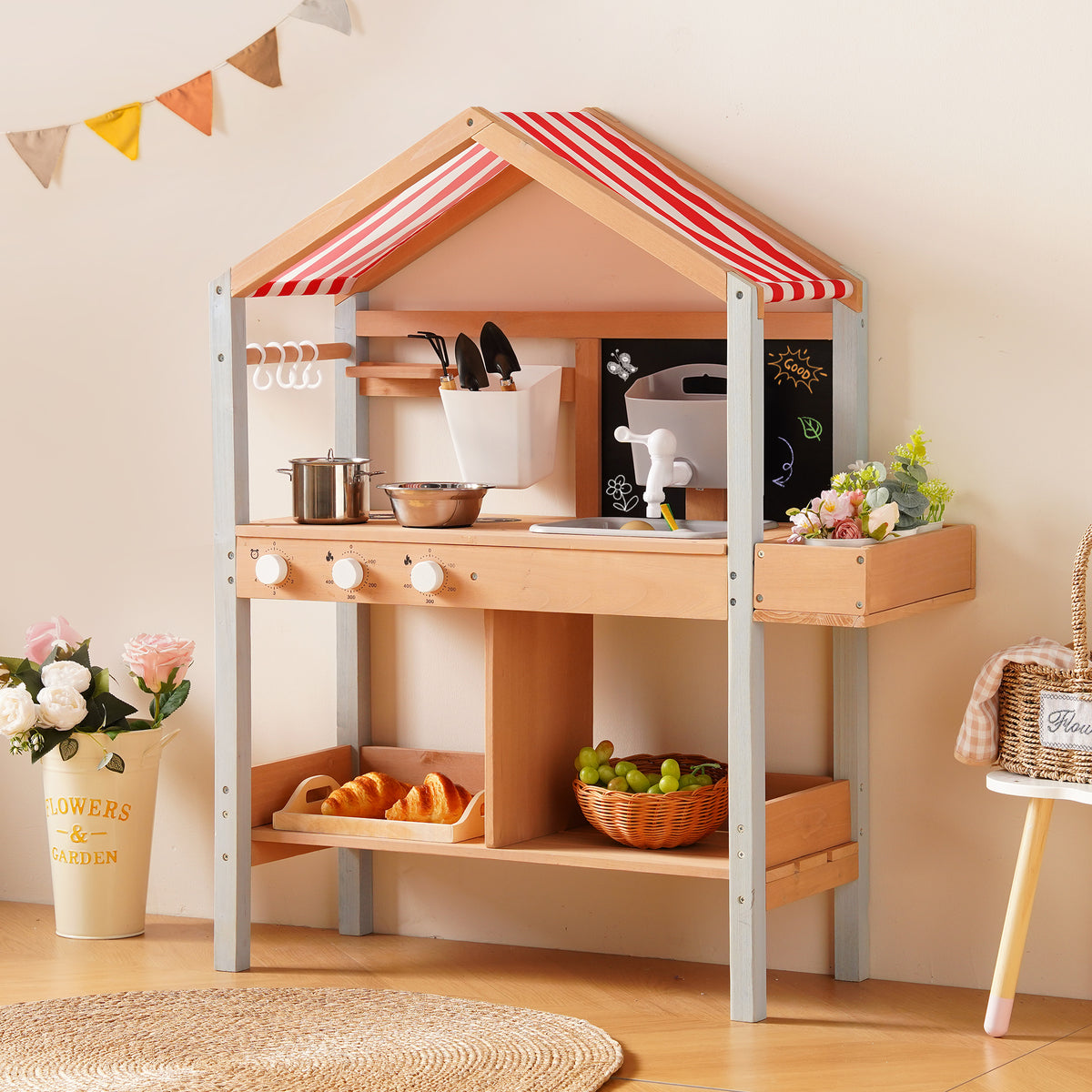 ROBUD outdoor mud kitchen placed outdoors among garden greenery showing chalkboard panel and accessory hooks without canopy