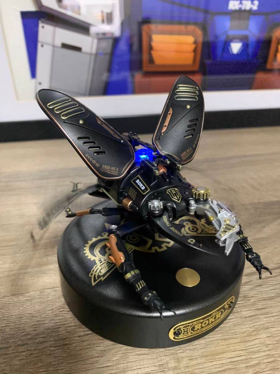ROKR black mechanical bee model with gold gear details and spread wings on a black display base