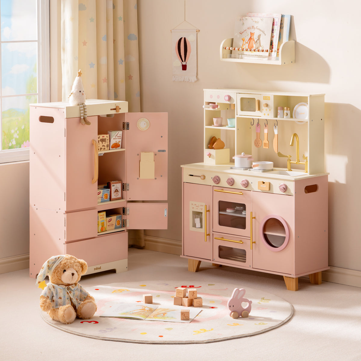 ROBUD Glowwood pink toy refrigerator next to the play kitchen, both with open shelving, shown in a tidy pastel playroom.