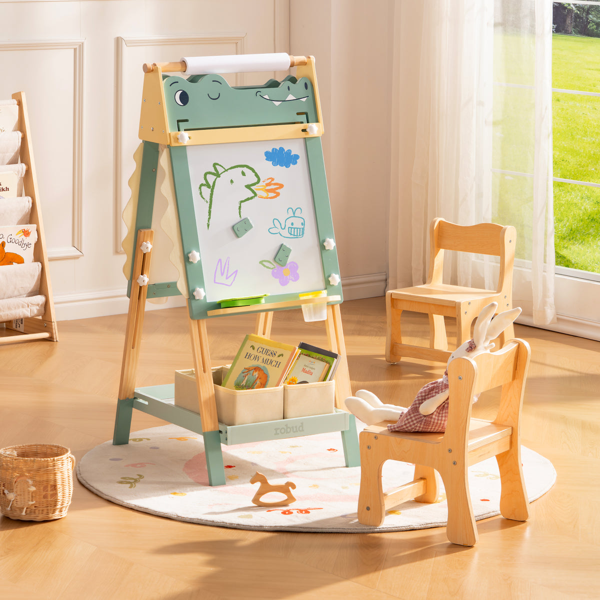 ROBUD double-sided whiteboard easel showing crayon drawings beside a natural wood storage shelf and small wooden chair.