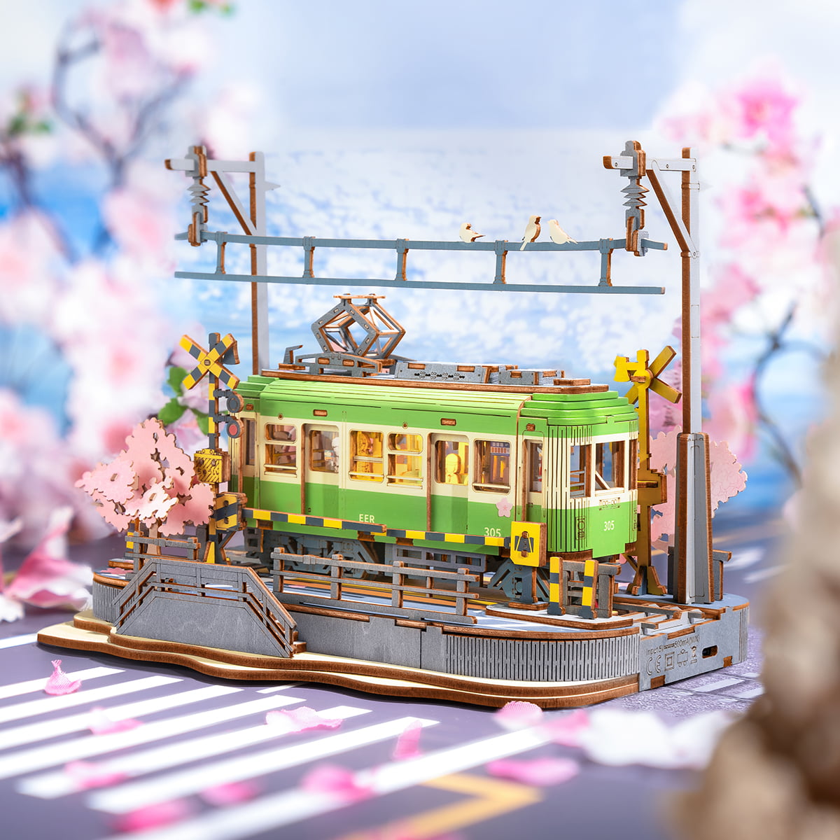Rolife Sakura Journey TGS02 green tram with pink cherry blossoms against blue sky and crossing signal posts