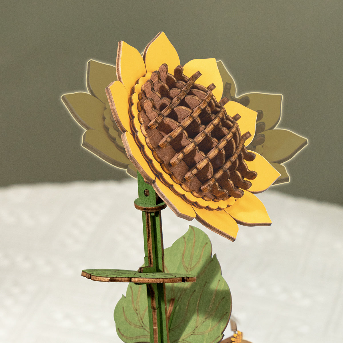 Rowood wooden sunflower model stands upright with layered yellow petals and green leaves.