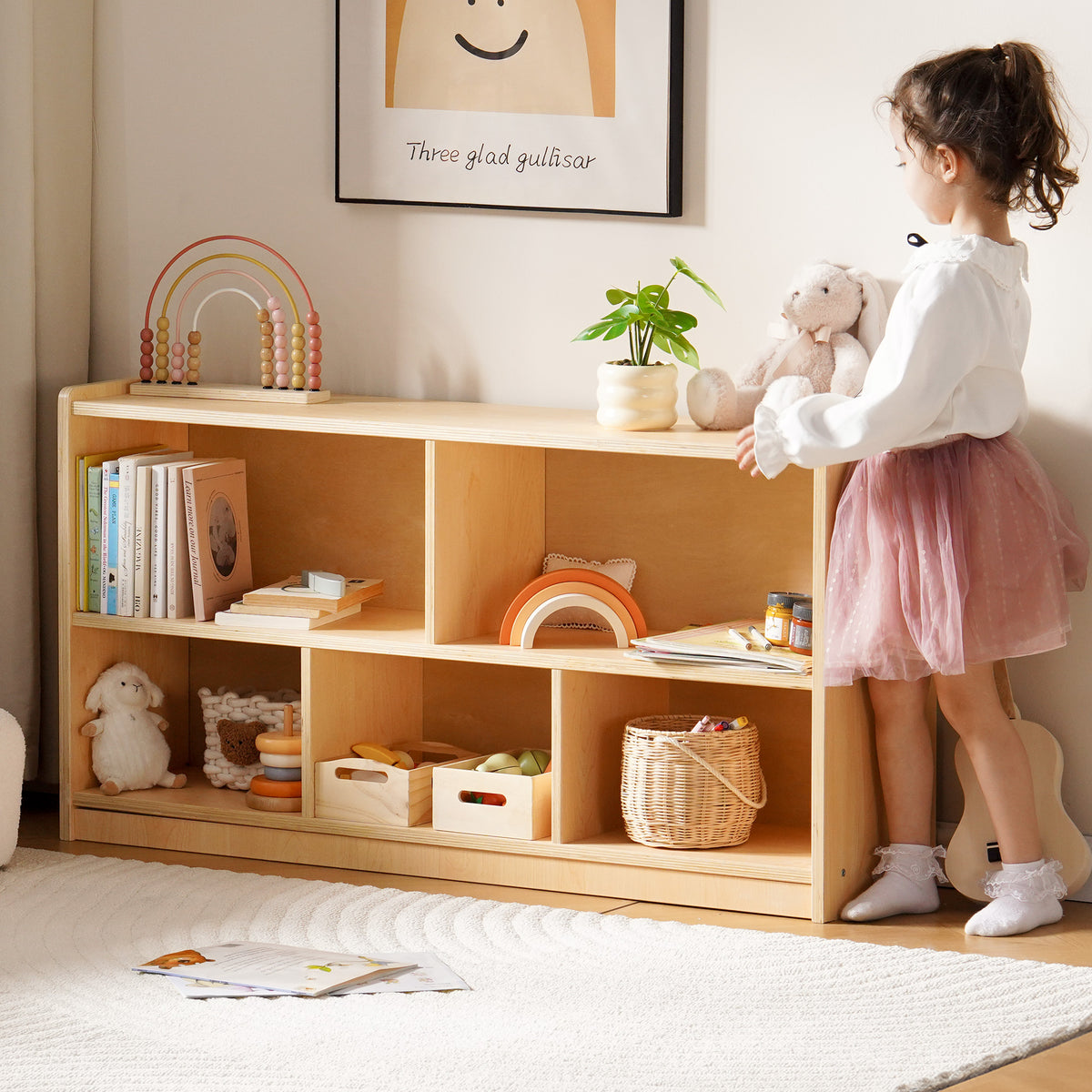 Young girl in pink skirt arranging toys on ROBUD Wooden Storage Cabinet with open shelves in a cozy pastel playroom