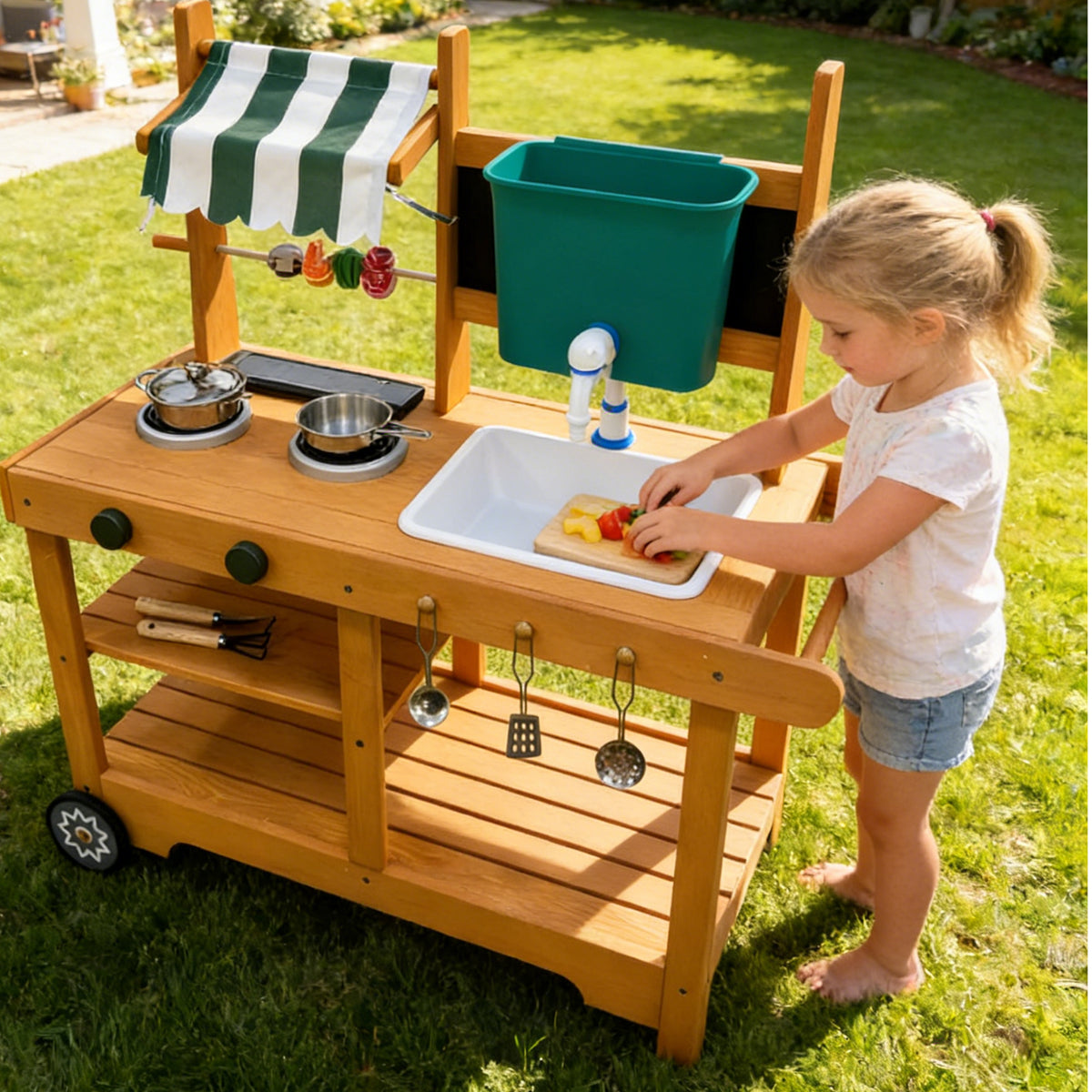 Blonde girl playing at ROBUD wheeled outdoor mud kitchen in a sunny backyard with accessories hanging and golden natural wood finish