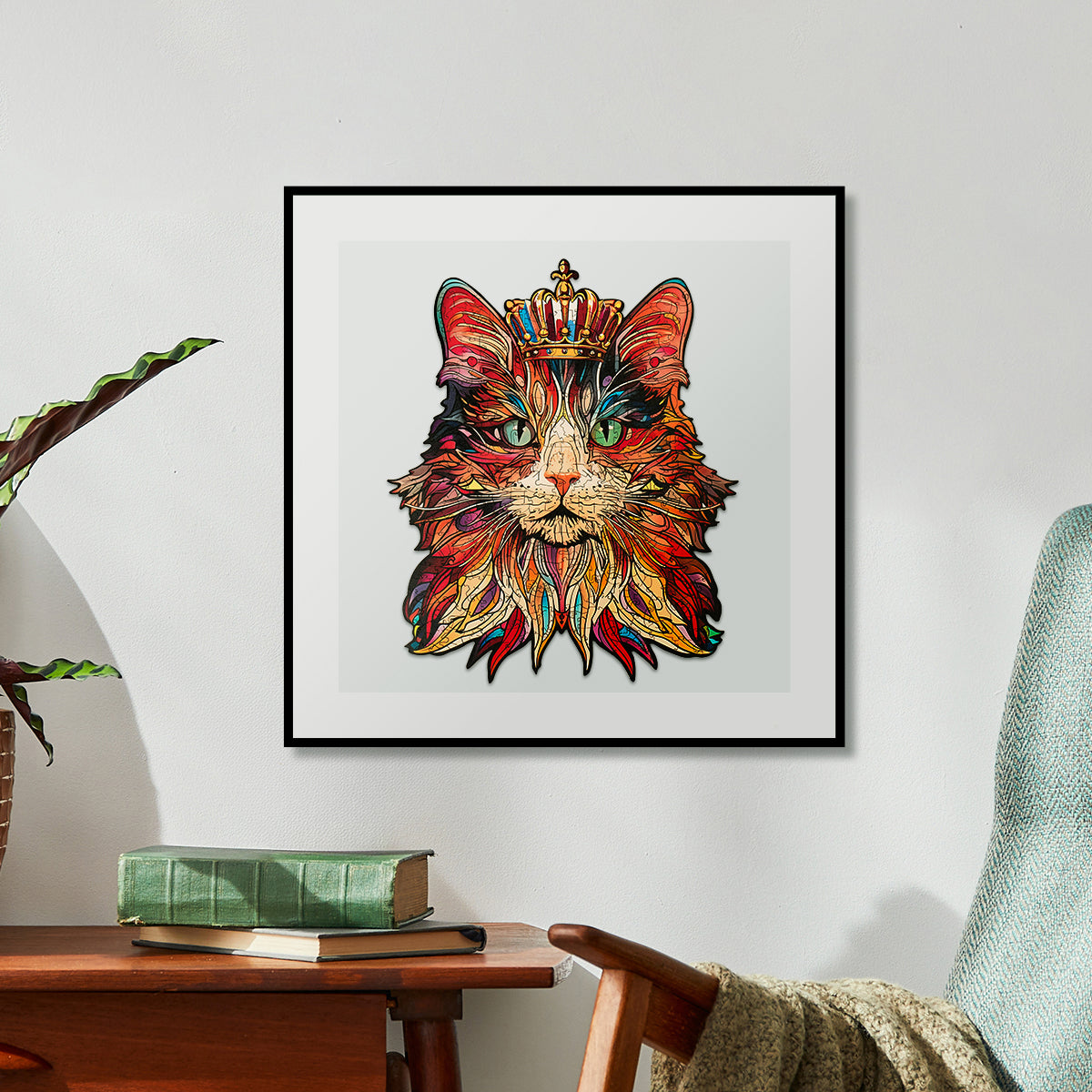 Framed completed orange and red cat portrait wooden puzzle displayed above a wooden desk with a plant beside it