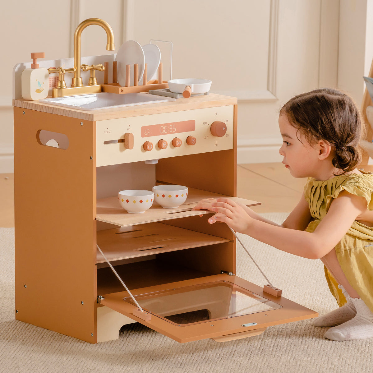 Toddler girl in yellow dress pulling out the lower drawer tray of ROBUD Wooden Caramel Dishwasher in nursery setting