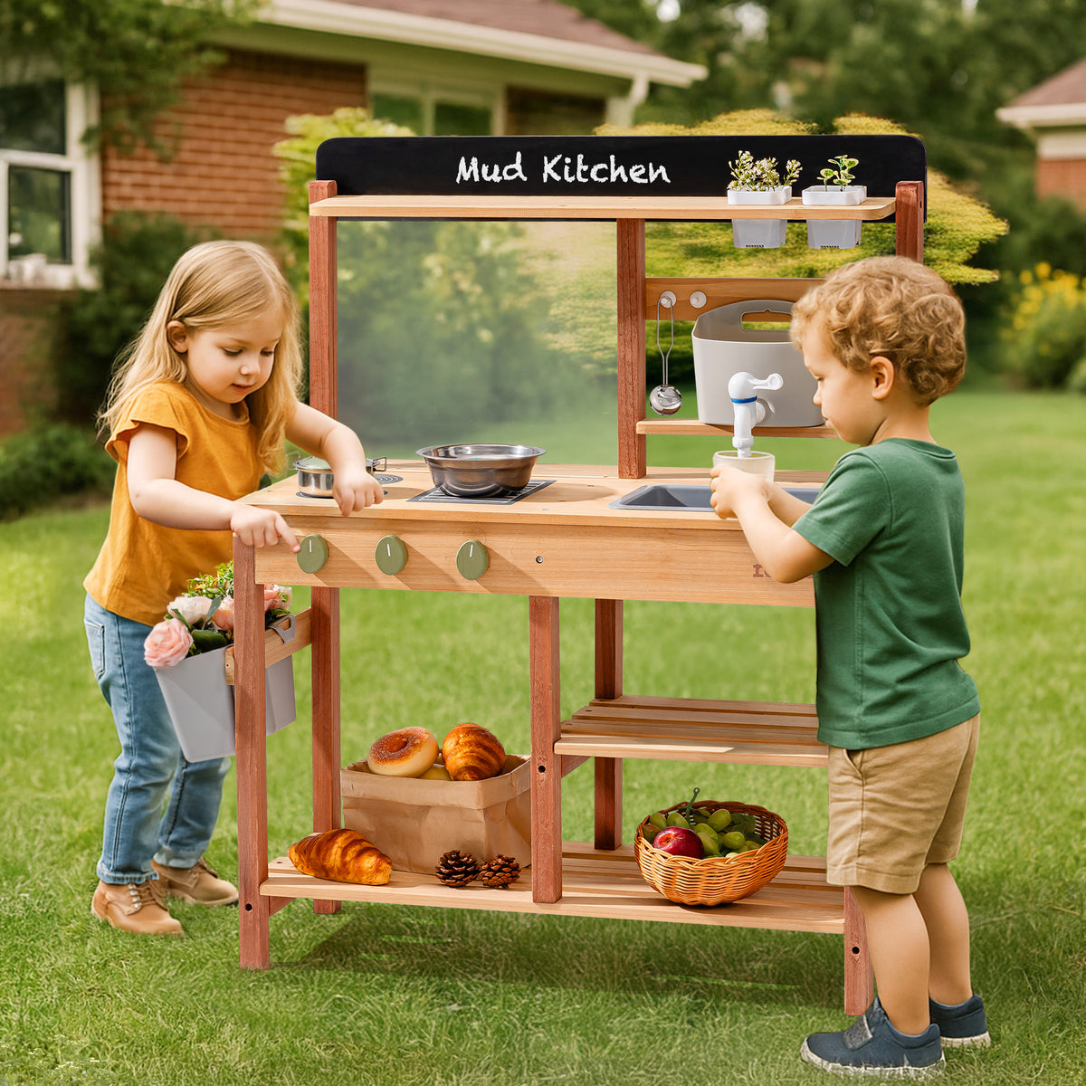 Two children playing together at the ROBUD outdoor wooden mud kitchen in a sunny grass yard, one loading flowers and one operating the water faucet