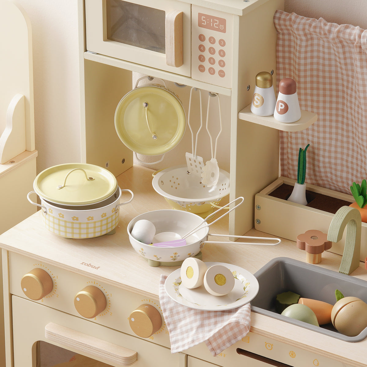 ROBUD Tinplate Pretend Cooking Utensils wooden play kitchen top view showing pink and cream pots, colander, plates and accessories neatly arranged