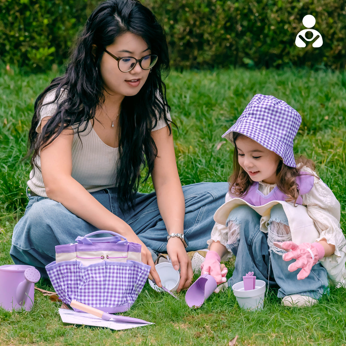 Girl in purple apron watering garden plants with ROBUD Kids Gardening Set lavender watering can among yellow wildflowers
