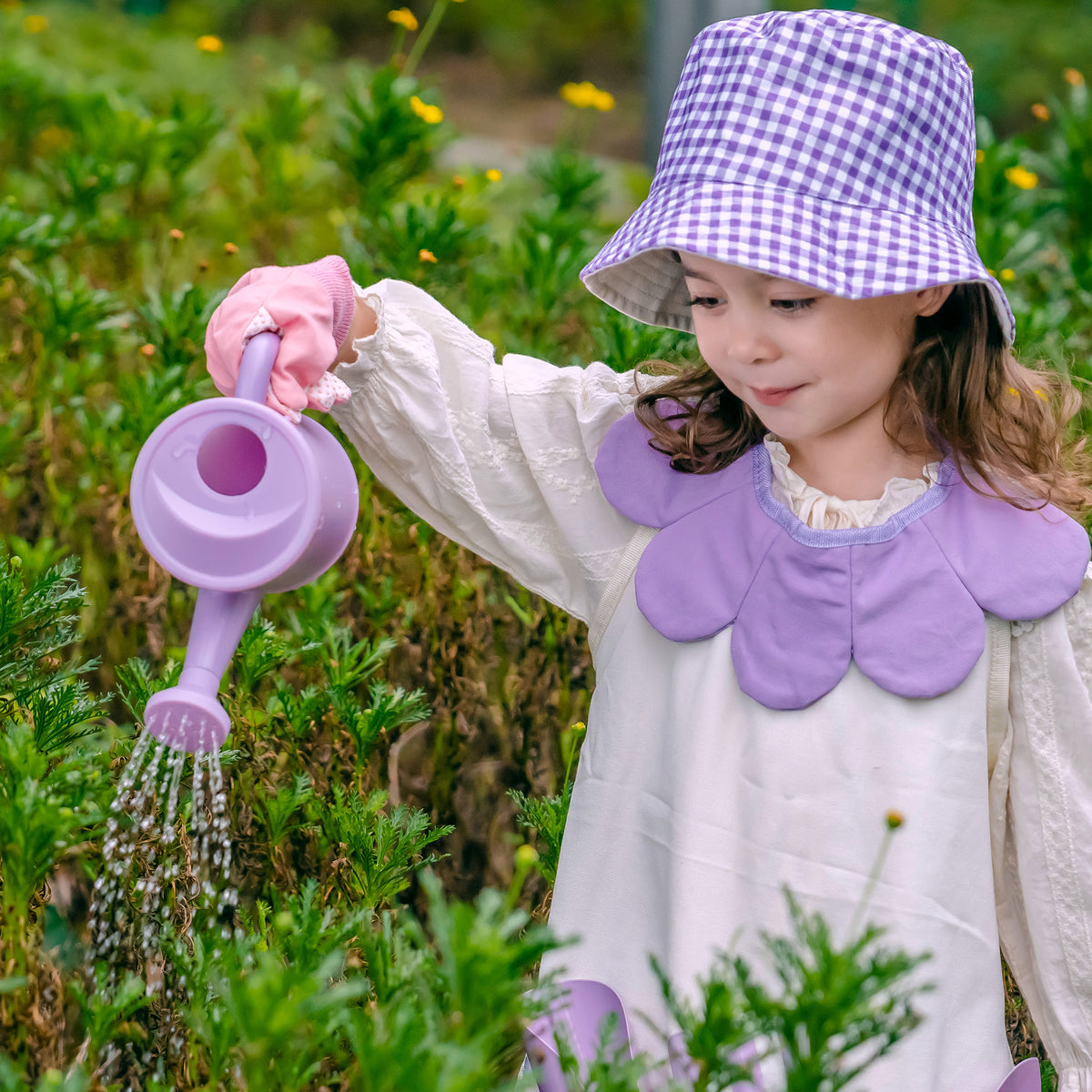 Girl in purple gingham hat kneeling on grass scooping soil into pot with ROBUD Kids Gardening Set purple shovel tool