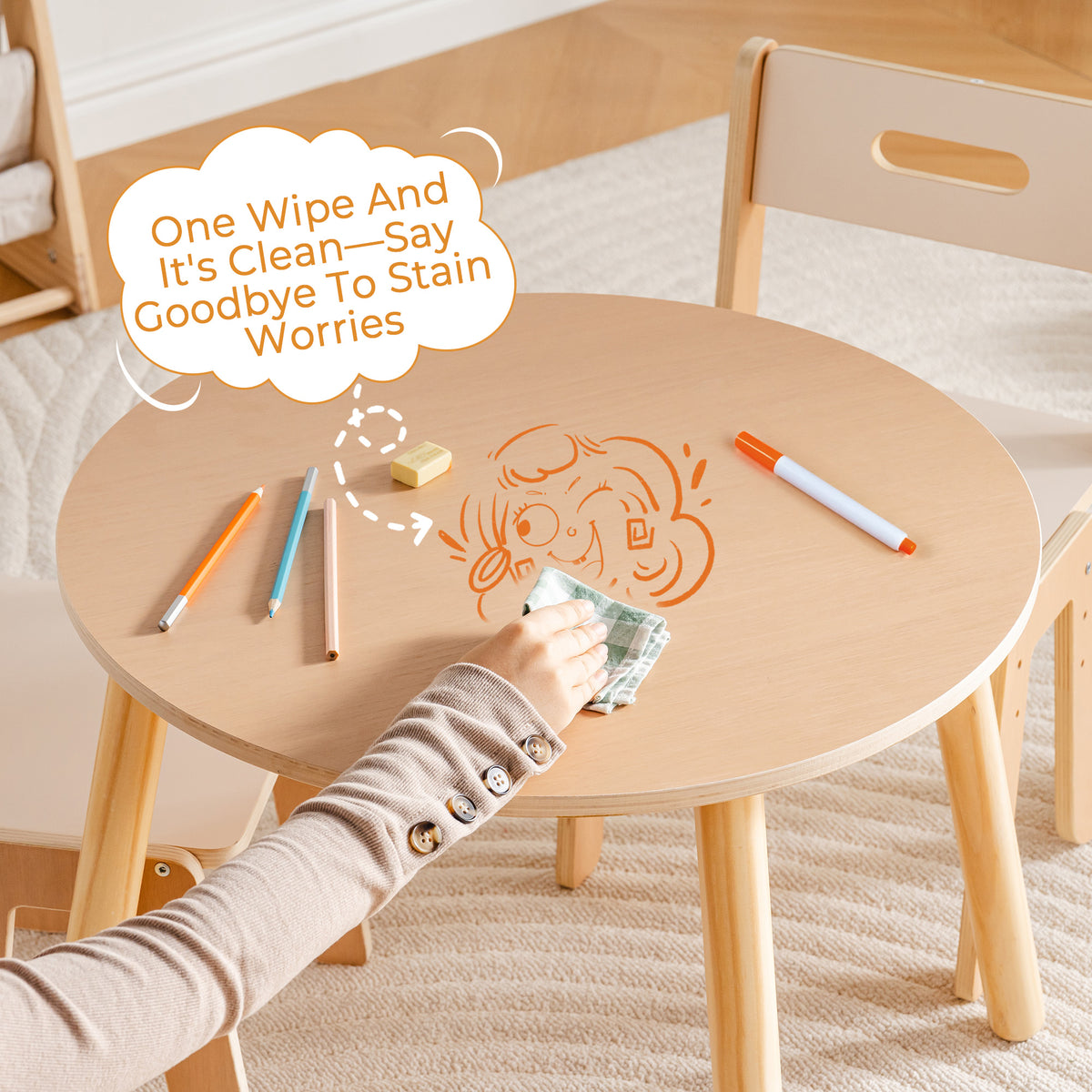 Child wipes a crayon doodle off the ROBUD round kids table with a cloth, showing the wipe-clean tabletop surface.