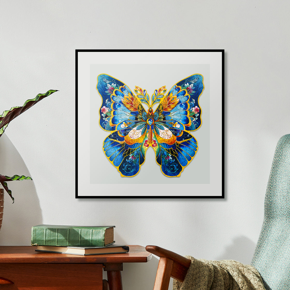 Framed completed blue butterfly wooden art puzzle displayed on a wall above a wooden desk in a bright room