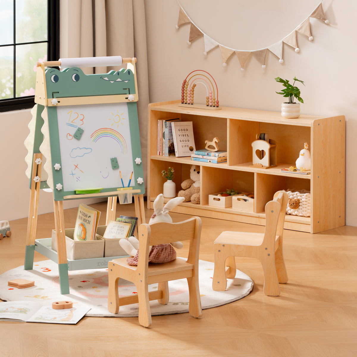 ROBUD whiteboard dinosaur easel and wooden storage bookshelf paired in a sunny room with garland banner overhead.