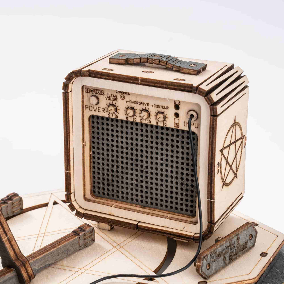 Close-up of ROKR wooden mini amp model showing engraved speaker grille and control panel knobs