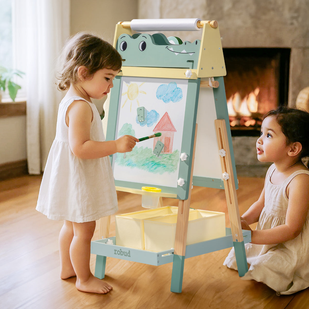 Two young children painting on ROBUD Crocodile Easel whiteboard together in front of a fireplace