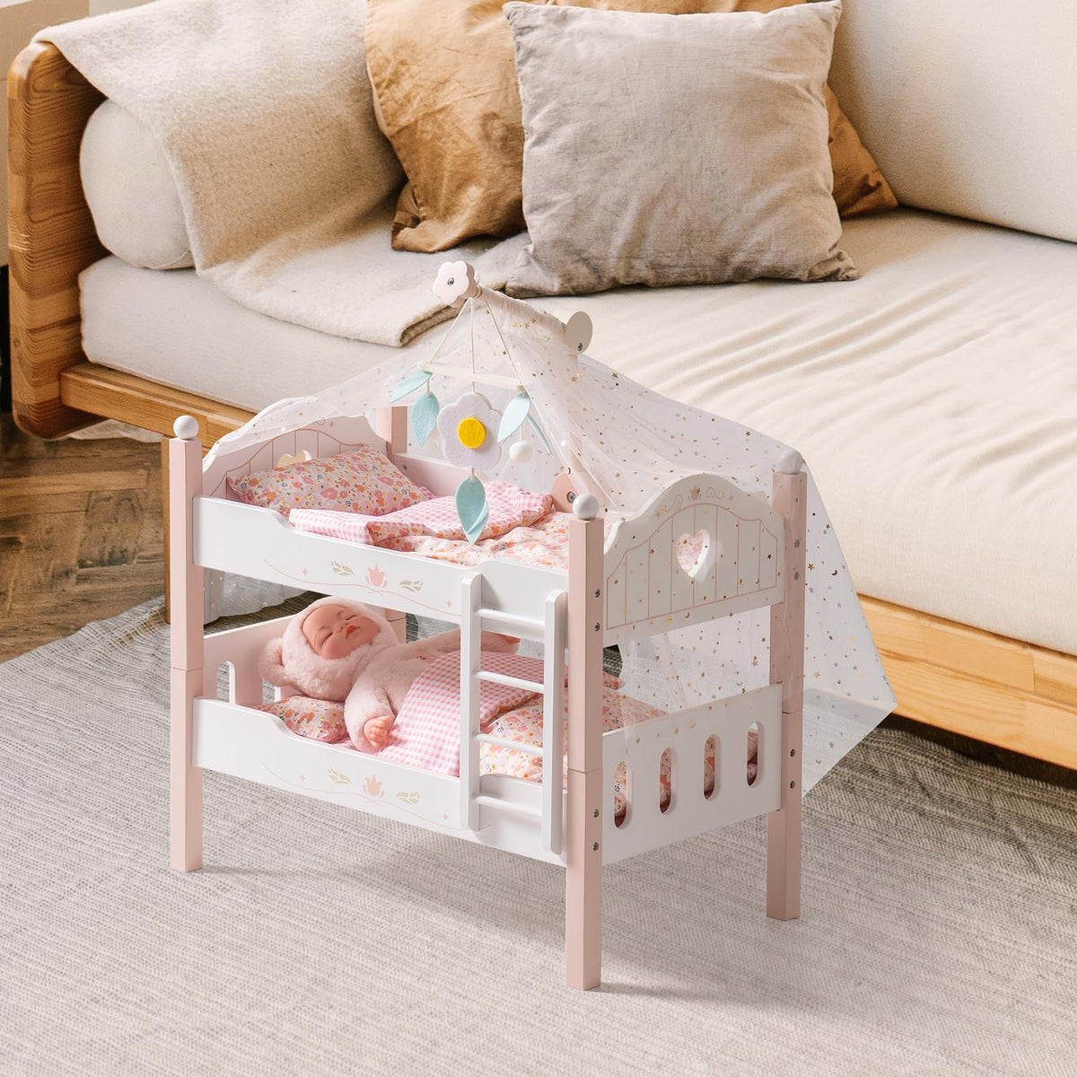 Robud pink wooden doll bunk bed with star canopy, floral bedding and a baby doll resting on the lower bunk, set beside a living room sofa