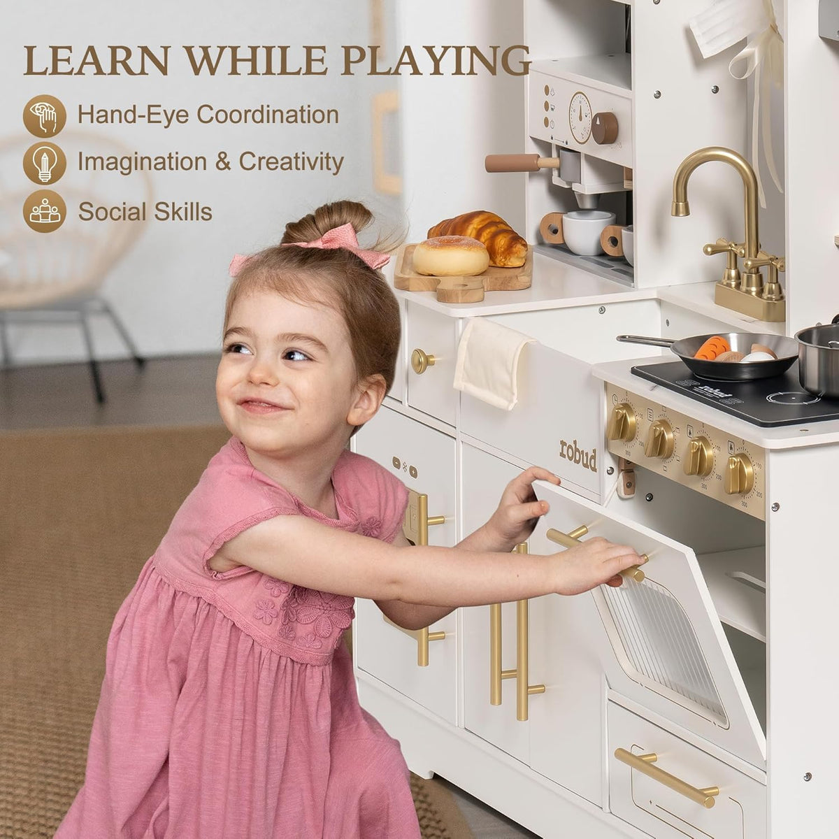 Two children playing side by side at the large ROBUD white wooden kitchen playset with gold hardware showing the espresso station, golden faucet sink and stove with pots in a warm home setting