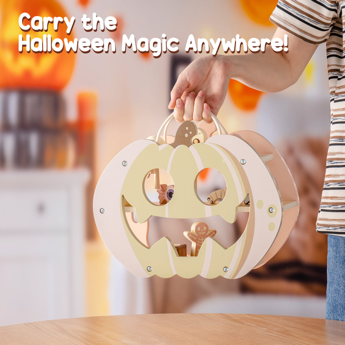 Child carrying ROBUD Halloween Candy House pumpkin playset by its handle while wearing a striped shirt in a warmly decorated kitchen