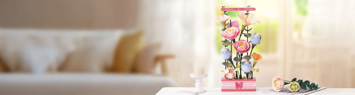Rowood Infinite Smiles AD011 PC banner, tall pastel bouquet of roses, tulips and daisies in a pink gift box on a bright white table