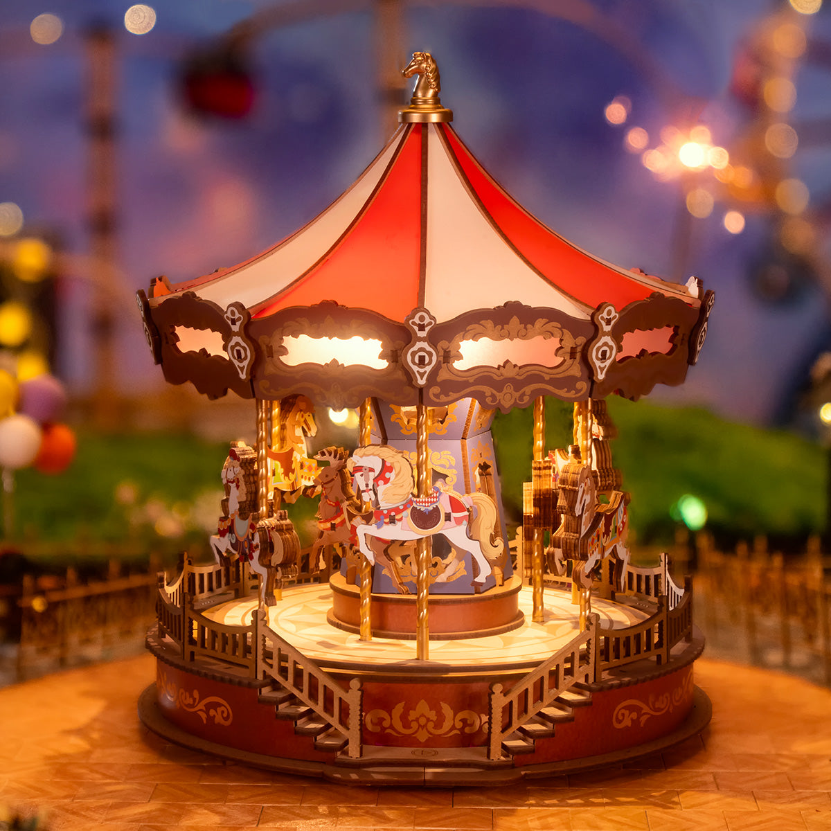 Rolife Classic Carousel AMC01 Music Dreamer illuminated at night with carousel horses spinning under red white canopy with bokeh lights behind