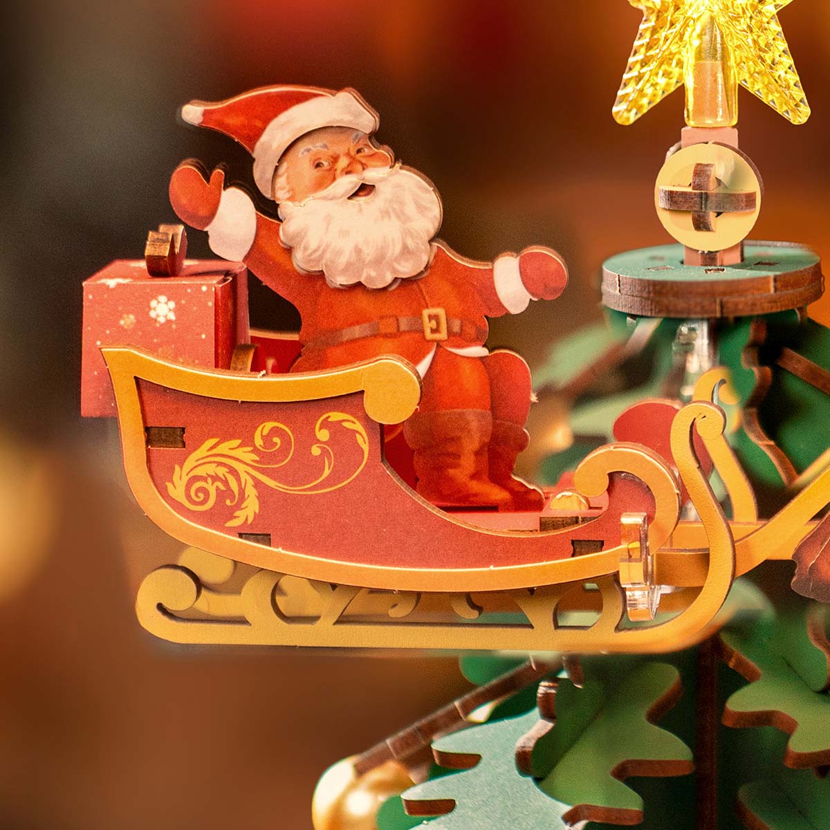 Rolife Christmas Melody Tree AMS01 close-up of warm LED light glowing through green layered tree branches with golden ornament ball detail