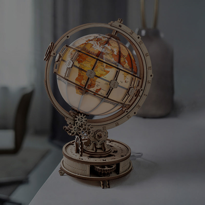 ROKR illuminated wooden globe puzzle on a desk with warm glow showing continents in amber tones, representing Robotime curious discovery products