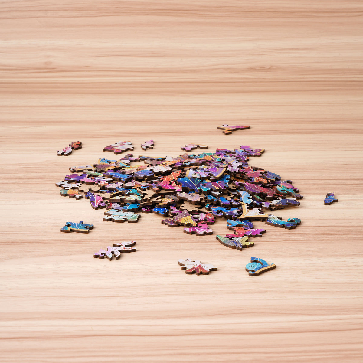 Rowood Mystic Mandala Flower wooden puzzle pieces spread across a light wooden surface before assembly with colorful petal shapes visible.