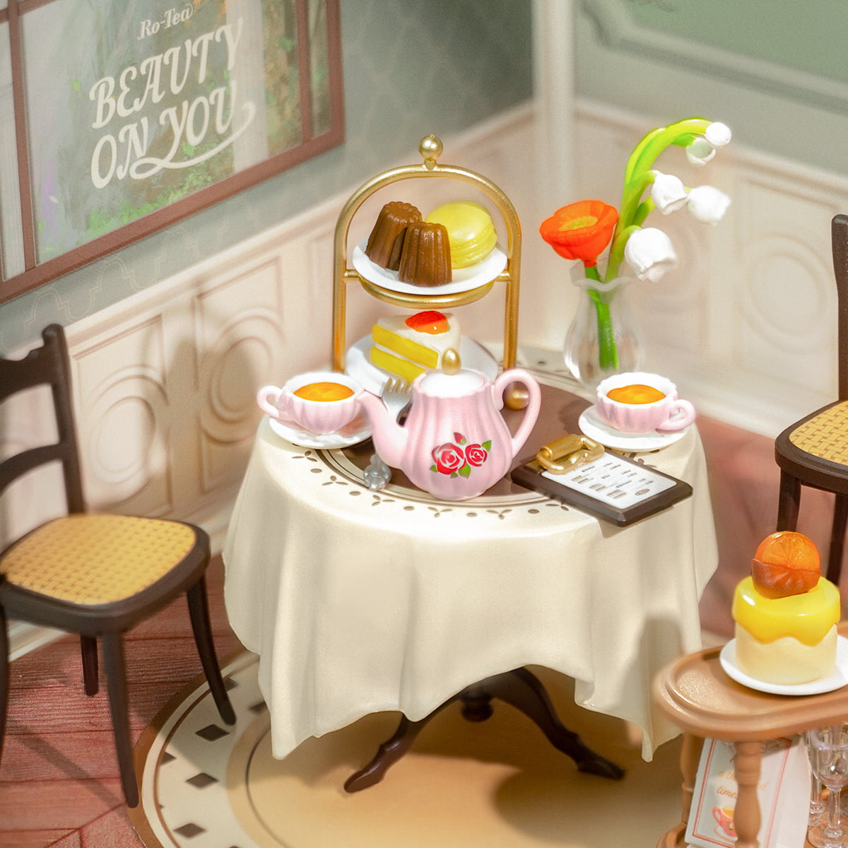 Rolife Sweet Sips Tea DW011 close up of the elegant afternoon tea table with pink teapot tiered dessert stand floral vase and china cups