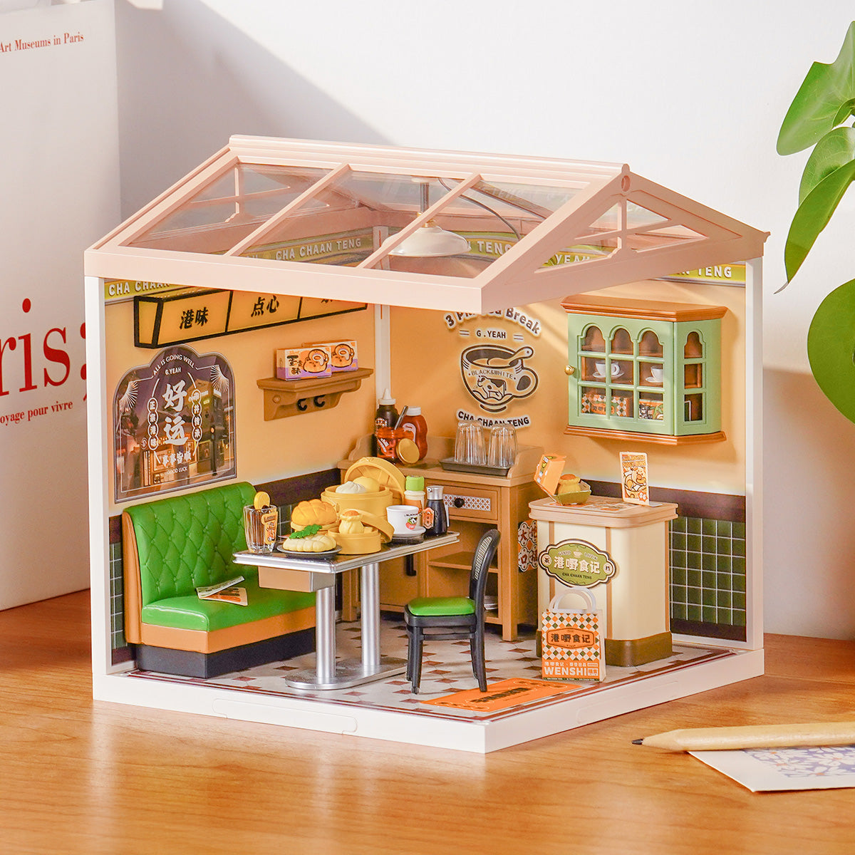 Rolife Hong Kong Bites Cafe DW021 Super Creator miniature house displayed on a desk with full interior view of cha chaan teng cafe with green seating and dim sum