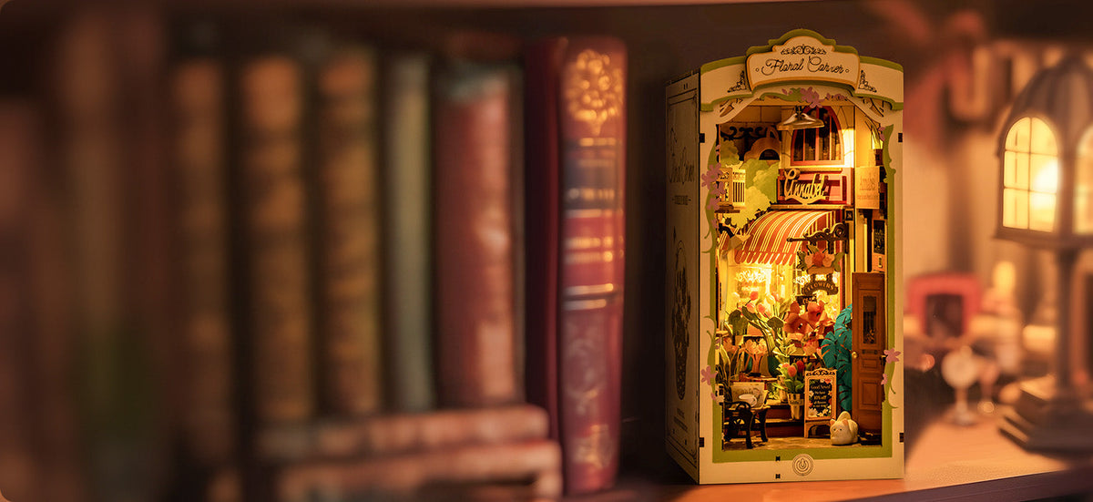 Rolife Floral Corner DIY book nook with a glowing flower shop interior tucked between vintage hardcover books on a warm wooden shelf.