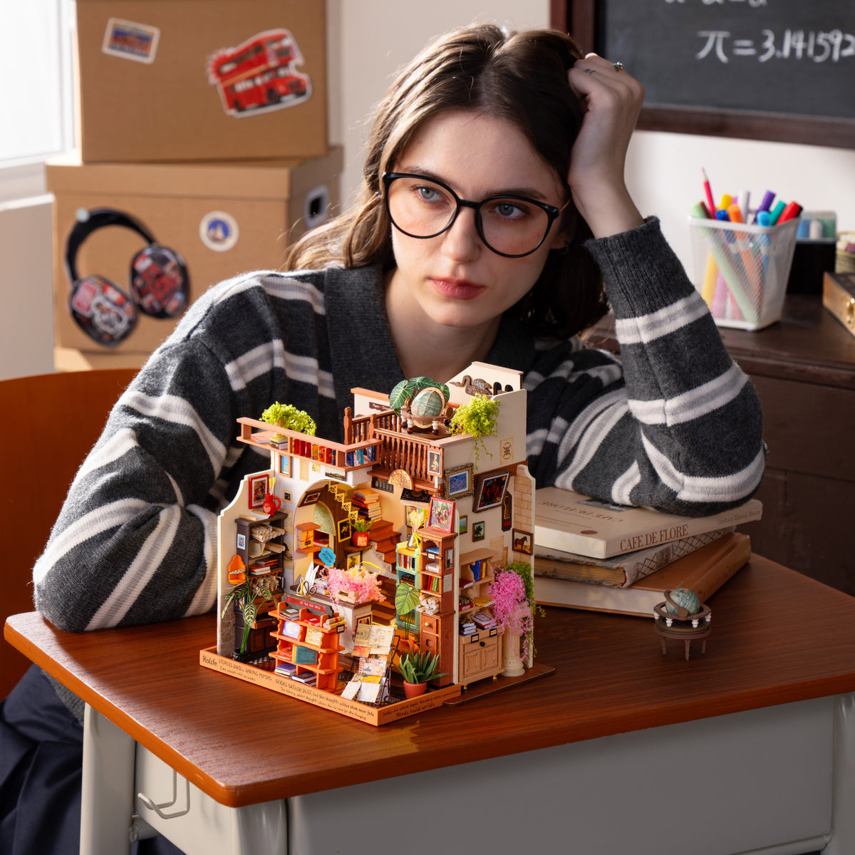 Woman resting her head on one hand beside a colorful PageStory Books miniature on a classroom desk