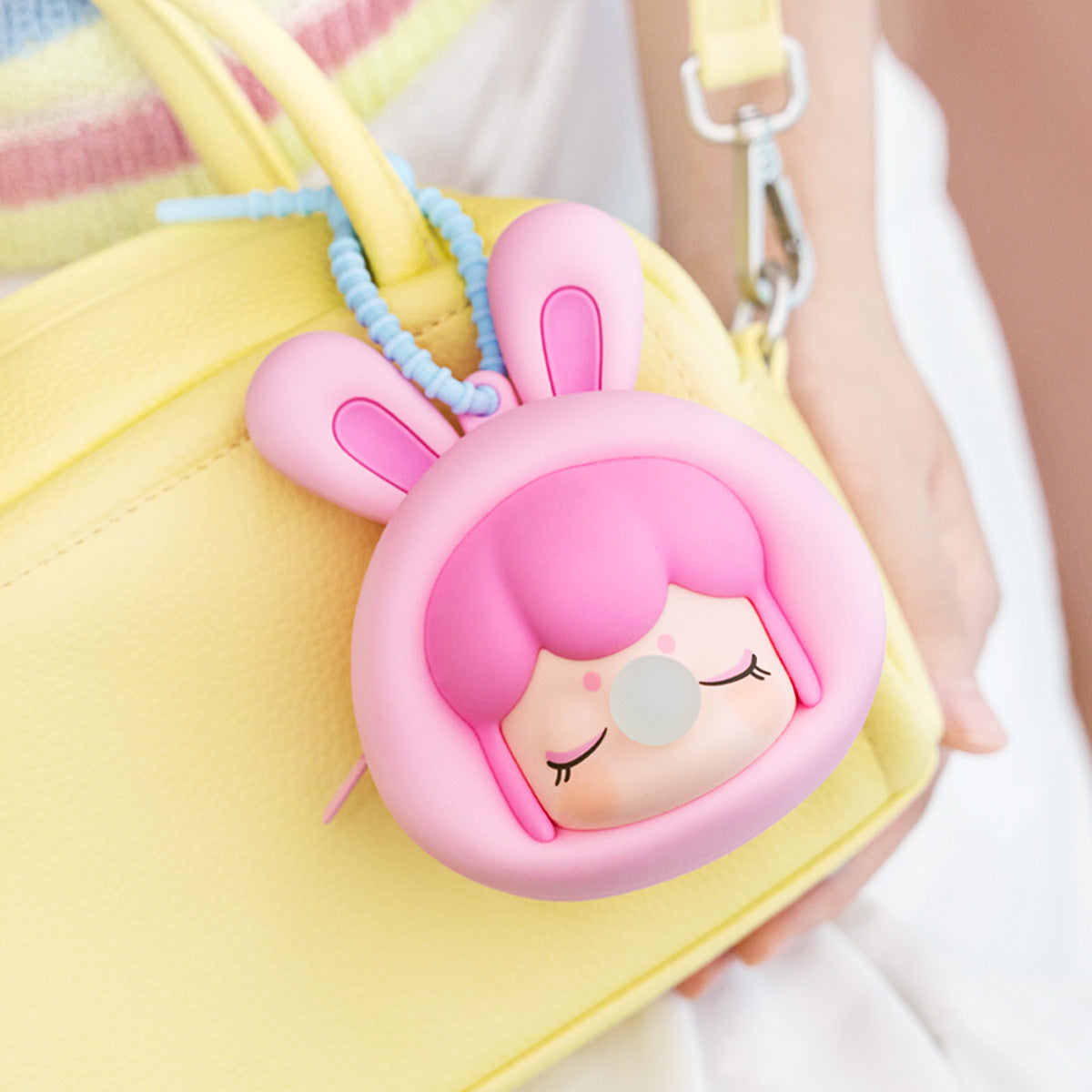 Rolife Baby Nanci Fluffy Party Headphone Case green bear variant phone charm hanging from a cream phone case held in a hand with jeans background