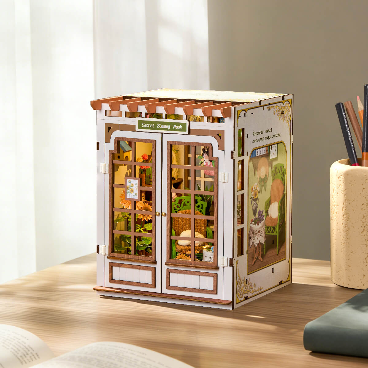 Rolife Secret Bloomy Nook book nook on a wooden desk beside a window, exterior closed view showing the flower shop facade