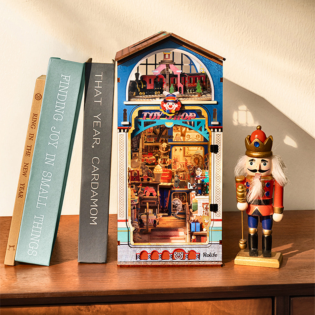 Rolife Treasure Toy Shop book nook displayed between books and a red nutcracker figure