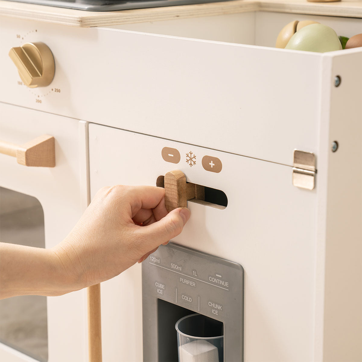 ROBUD white play kitchen coffee machine slot detail with a hand inserting a toy coffee capsule.