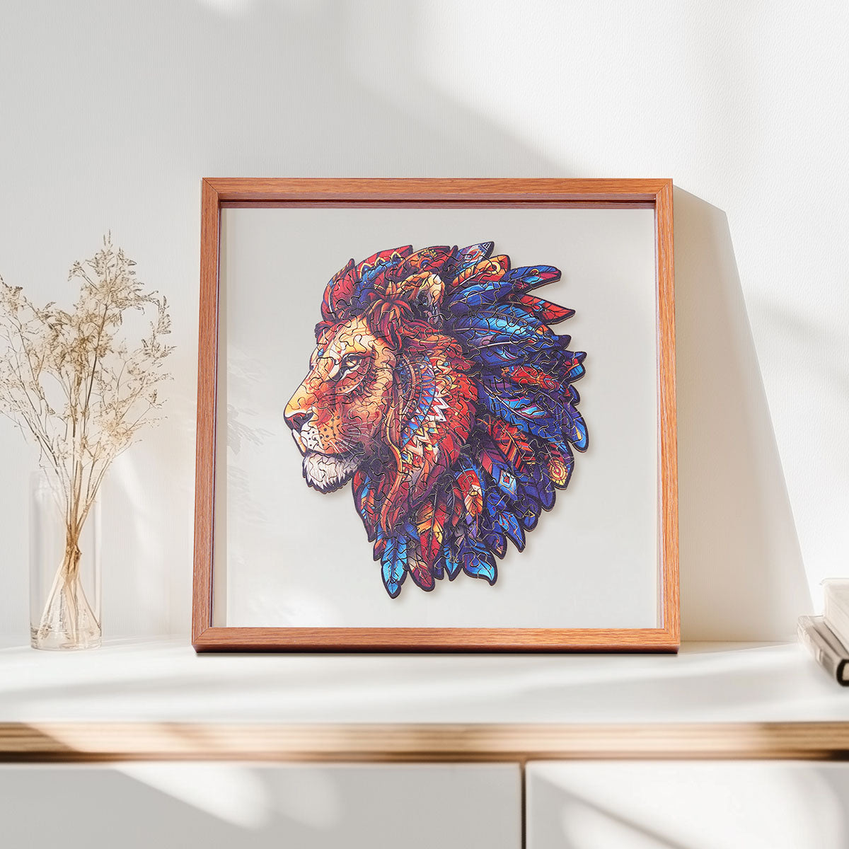 Rowood Lion King wooden jigsaw puzzle in a shadow box frame resting on a shelf beside dried flowers and a small ceramic vase