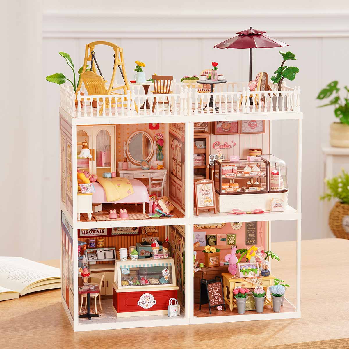 Rolife Super Creator Series 4-in-1 Four Grid miniature with a swing balcony and four rooms including bedroom, bathroom with clawfoot tub, kitchen, and Rolife living room on a wooden desk.
