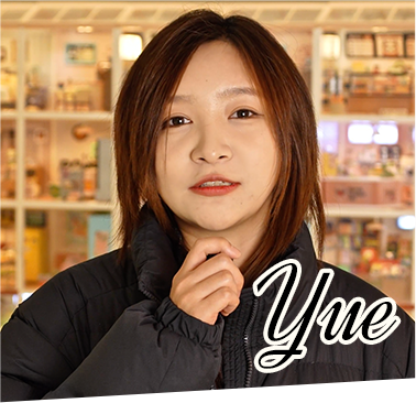A Rolife team member named Yue poses in front of a brightly lit retail store filled with Rolife miniature houses and collectible products