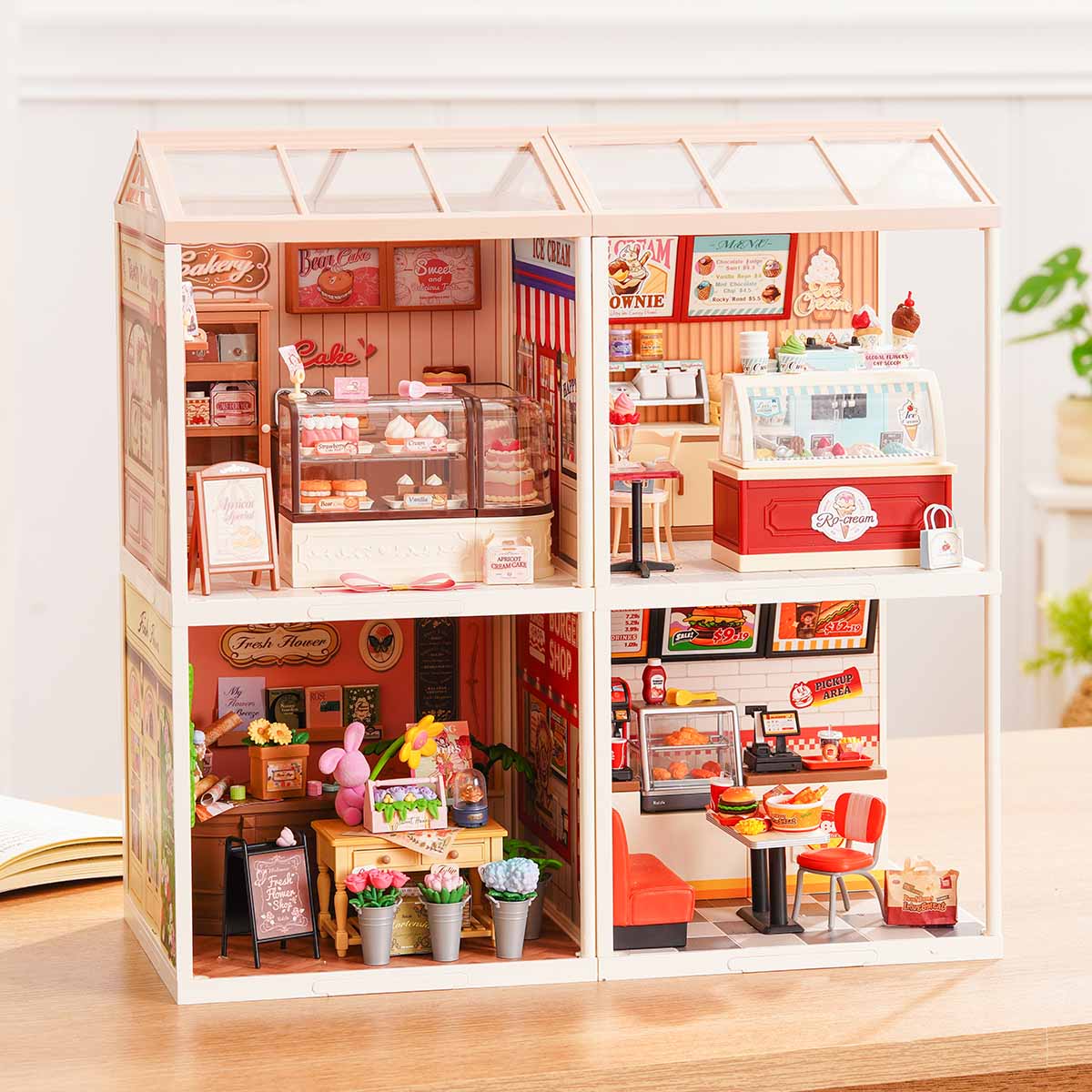 Rolife Super Creator Series 4-in-1 Four Grid miniature with burger diner, afternoon tea, Rolife Bar, and bubble tea rooms in a two-by-two grid with umbrella and balcony on a table.