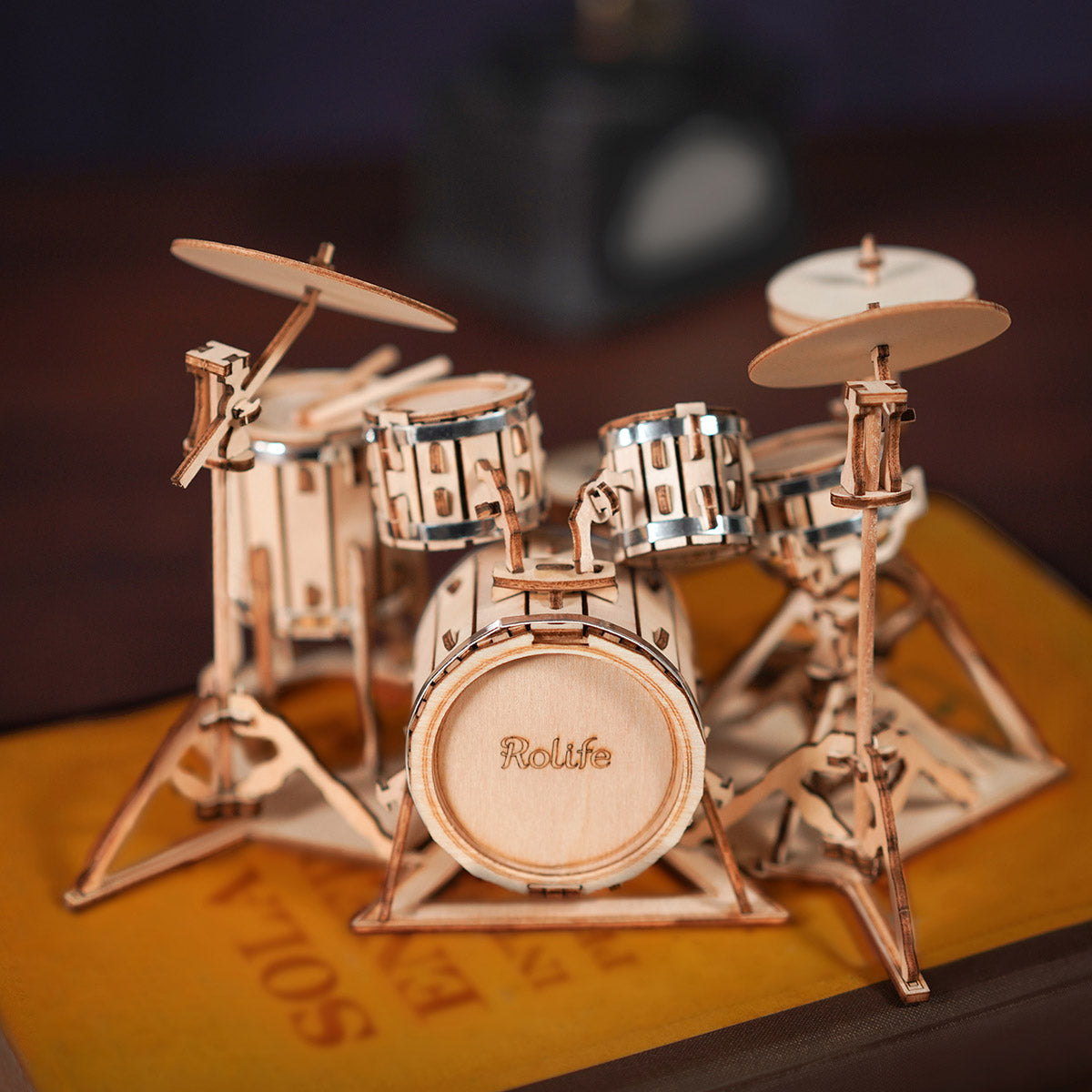 Rolife Drum Kit TG409 miniature wooden drum set with cymbals on a warm surface with soft bokeh