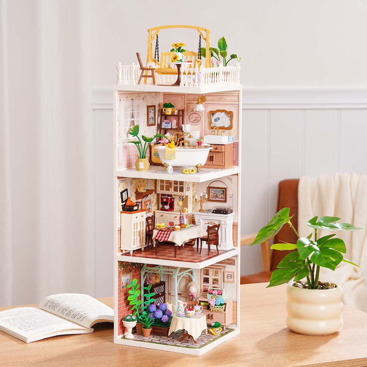 Rolife Super Creator Series 3-in-1 I Shape pink home miniature with swing rooftop, bathroom, elegant dining room, and garden tea room modules on a wooden surface beside a plant.