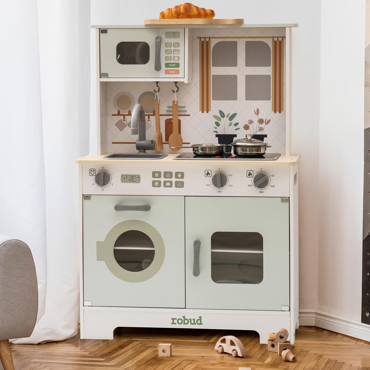 Robud green play kitchen side view with open cabinet and drawer in sage green and natural wood.