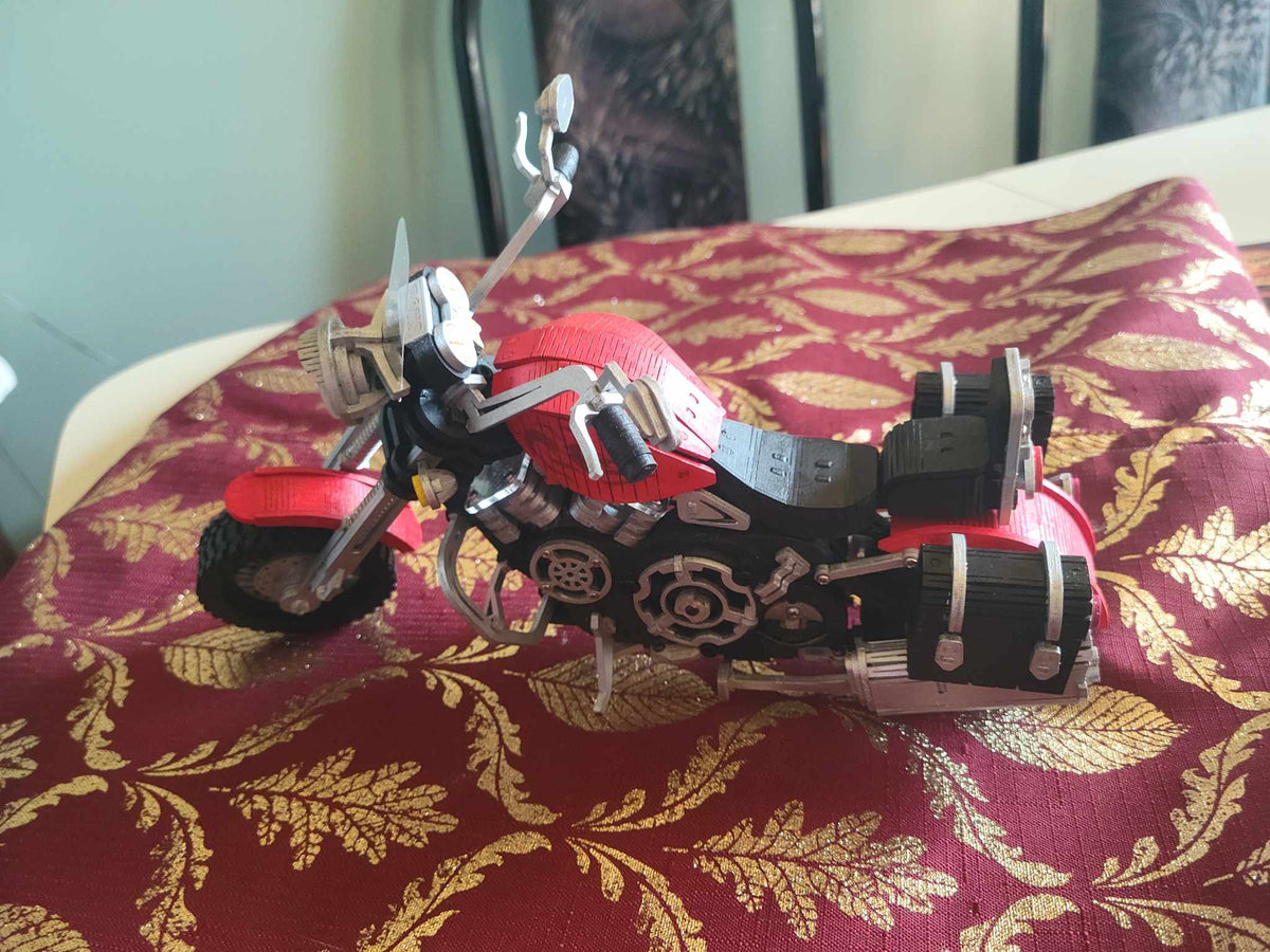 Robotime black and red race car model rests on patterned fabric.