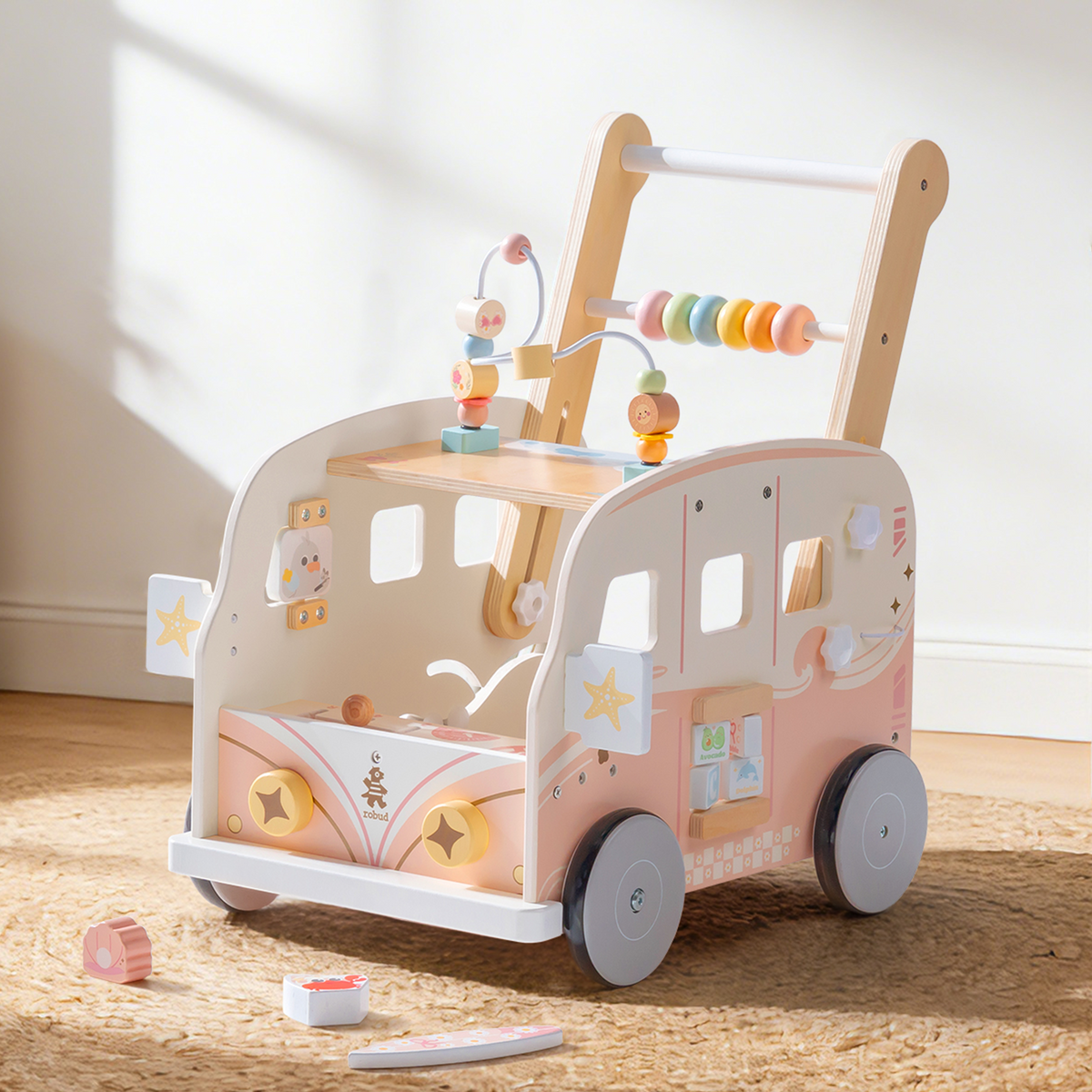 ROBUD pink tropical vacation bus wooden push walker shown on a neutral rug with activity panels facing forward.