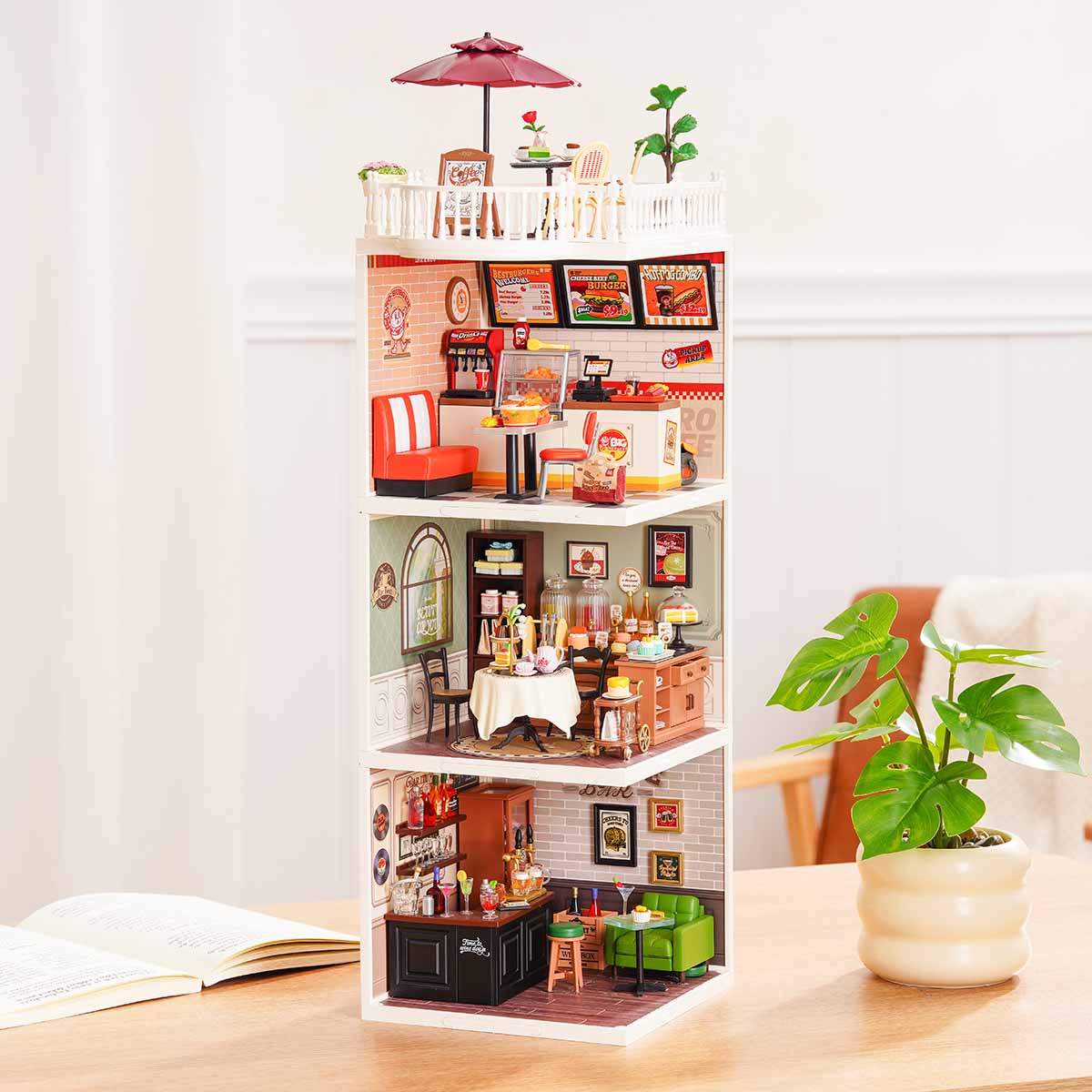 Rolife Super Creator Series 3-in-1 I Shape miniature with burger shop on top, afternoon tea cafe in the middle, and Rolife Bar at the base displayed on a wooden desk with a red umbrella rooftop.
