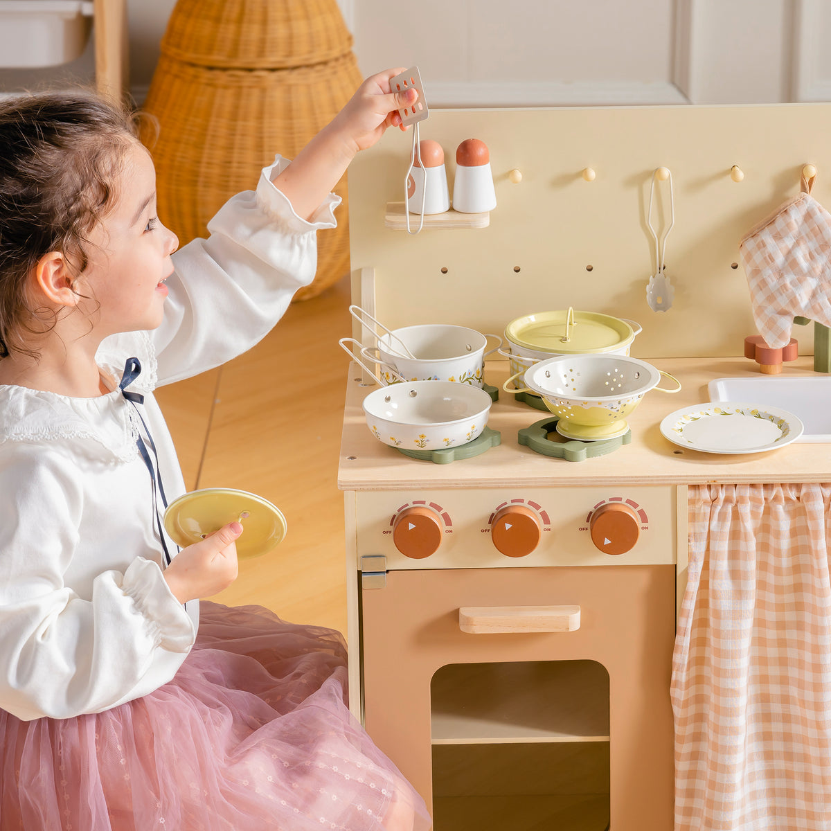 Girl in chef hat arranging food on pink plates at wooden ROBUD Tinplate Pretend Cooking Utensils play kitchen with accessories on counter