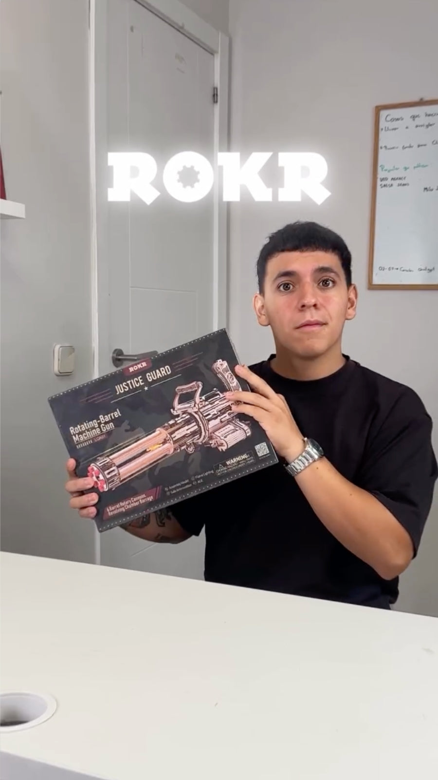 Man presenting a black ROKR mechanical model kit box in a bright office