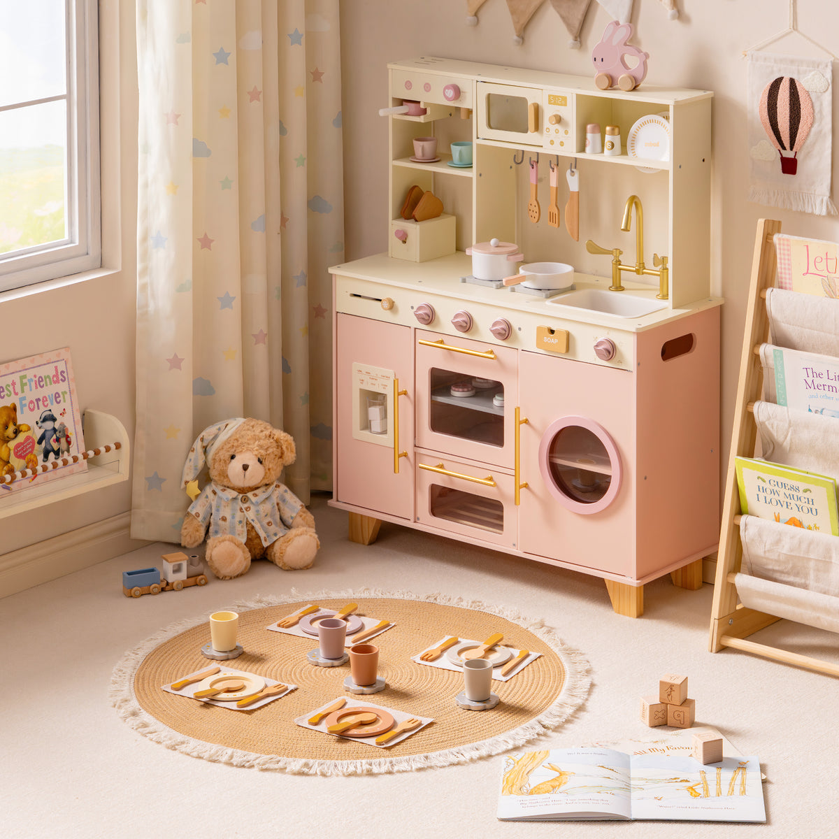 Side angle of the ROBUD Glowwood pink toy kitchen showing the washer drum, hanging utensils, and gold-toned faucet detail.